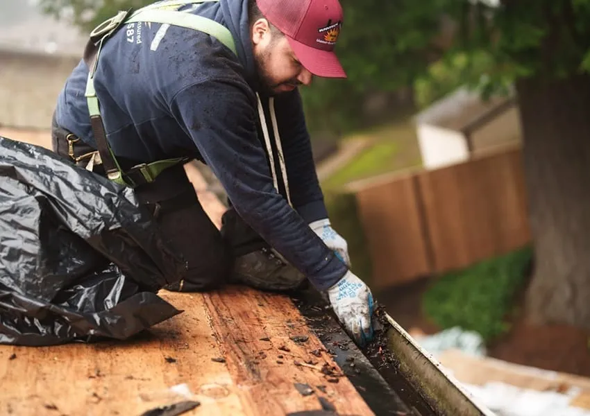 Sunnyside Roofing worker cleaning a residential gutter system