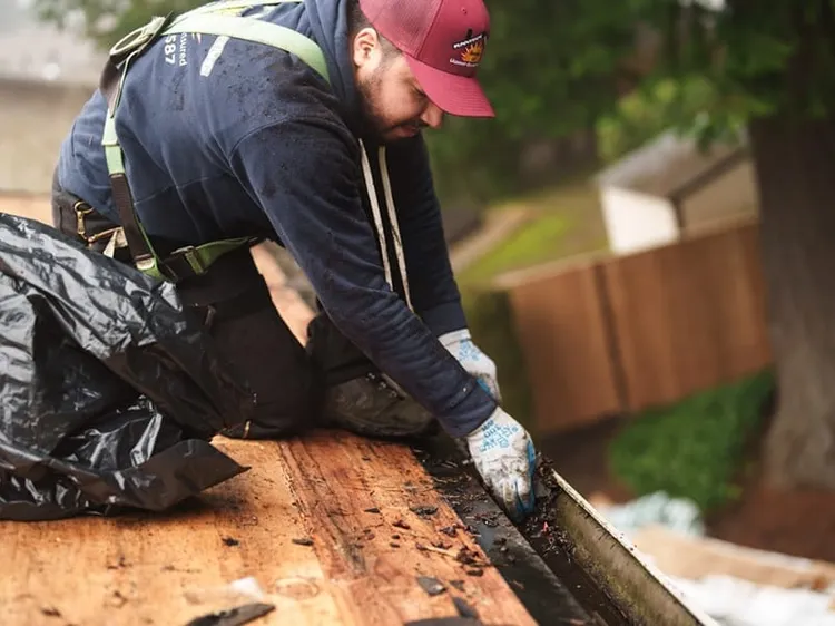 Sunnyside Roofing worker cleaning a residential gutter system